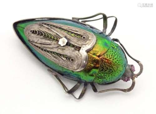A beetle brooch with white metal mounts, red stone eyes and ...