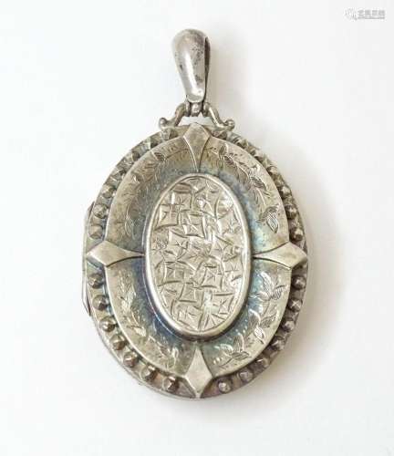 A Victorian silver locket formed pendant with engraved folia...