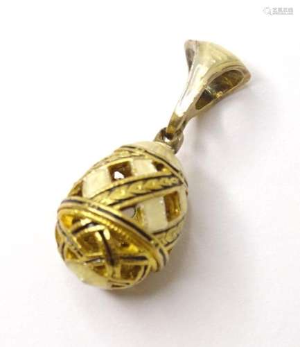 A gilt metal pendant charm of egg form with enamel decoratio...