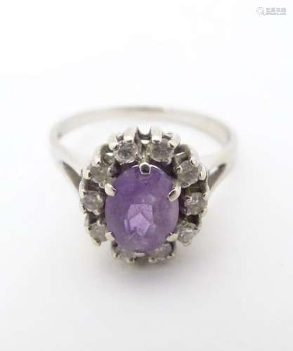 A 14ct white gold ring set with central amethyst bordered by...