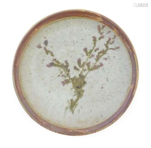 A studio pottery plate decorated with a stylised floral spra...