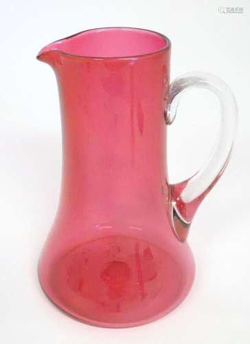 A cranberry glass jug with clear glass loop handle. 10"...