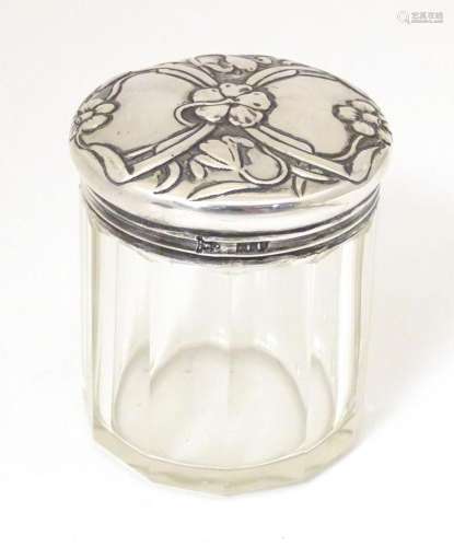 A glass dressing table jar with silver top having embossed A...