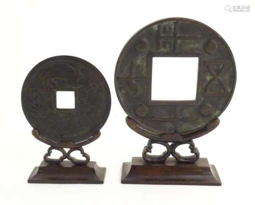 Two oversized cast replicas of Chinese cash coins on carved ...