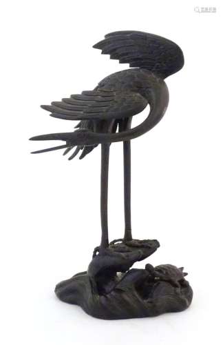 A Japanese cast bronze model of a crane standing on a rocky ...