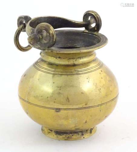 A brass water pot with bulbous body and swing handle with ha...