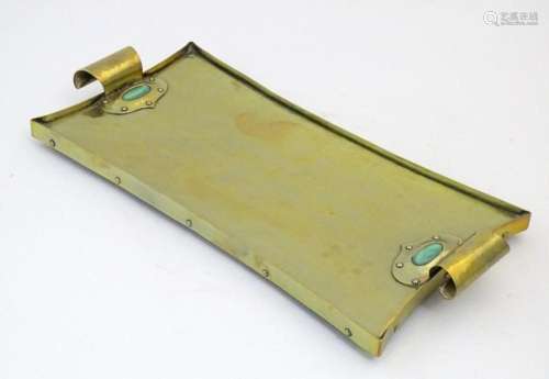 An Arts & Crafts brass tray with twin scroll handles and...