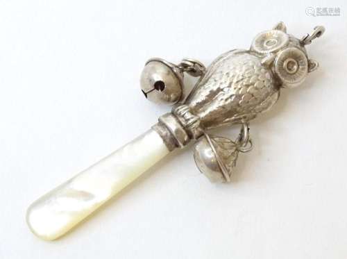 A childs rattle, the mother of pearl teeth surmounted by a s...