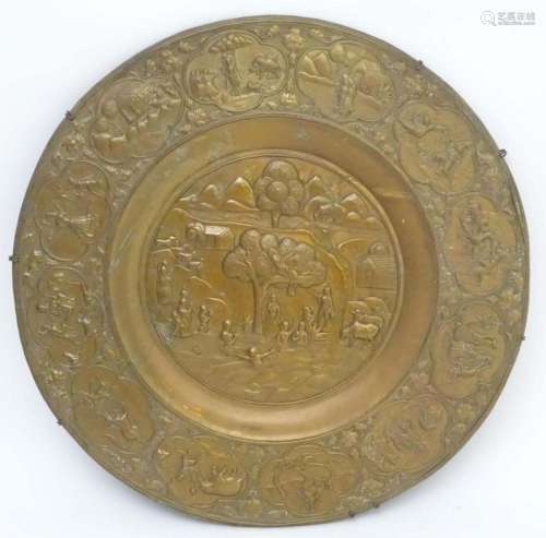 A large 20thC Indian brass charger with embossed decoration ...