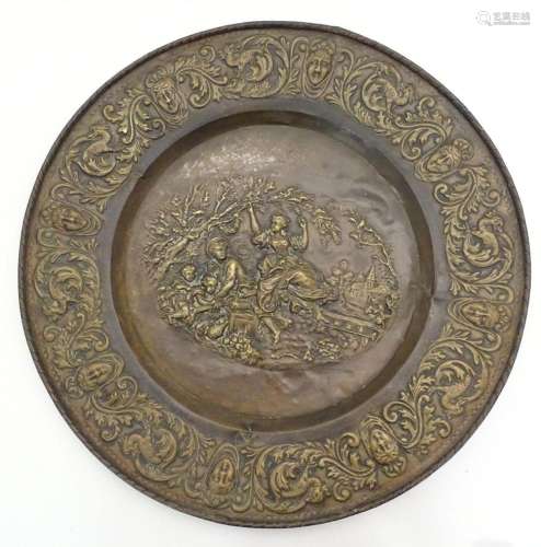 A large 20thC Continental embossed brass charger decorated w...