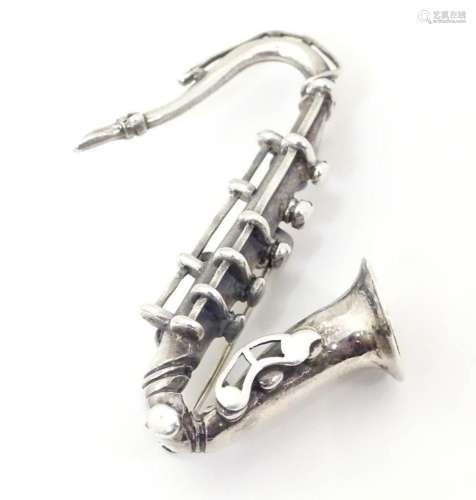 A silver brooch formed as a saxophone. Approx 2" long