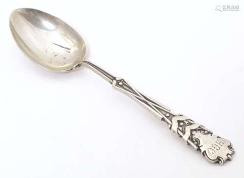 A silver teaspoon the handle with gold club and ball decorat...
