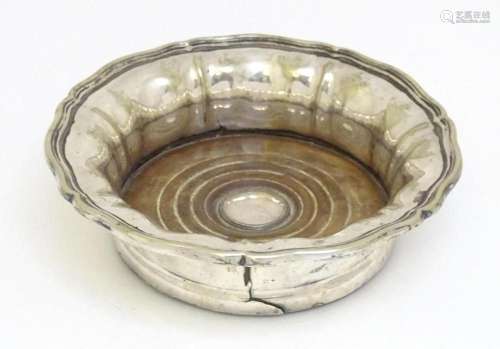 A silver plate wine coaster with turned wooden base. Approx....