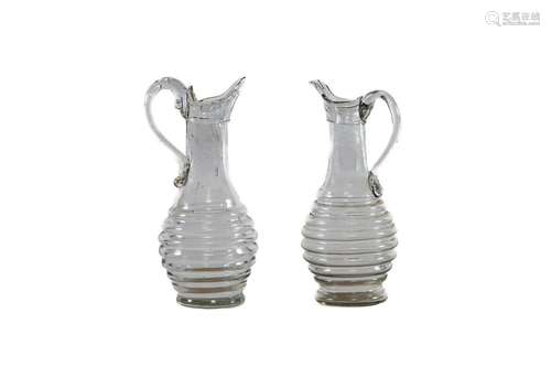 A pair of hand-blown clear glass ribbed ewers, French circa ...