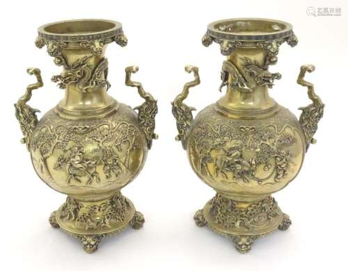 A pair of Oriental brass vases with twin handles formed as s...