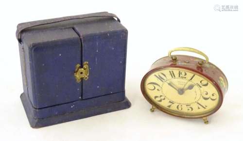 A 20thC French red lacquered travelling alarm clock with chi...