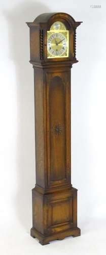 An oak cased grandmother clock with brass dial flanked by ba...