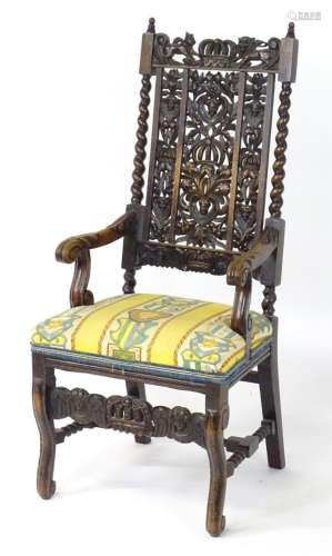 A late 19thC oak open armchair, having a heavily carved cres...