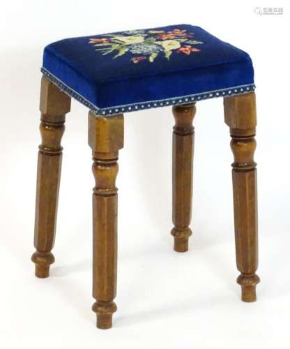A Victorian walnut stool with a floral needlework top above ...