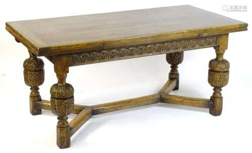 An early 20thC oak draw leaf dining table with a carved frie...