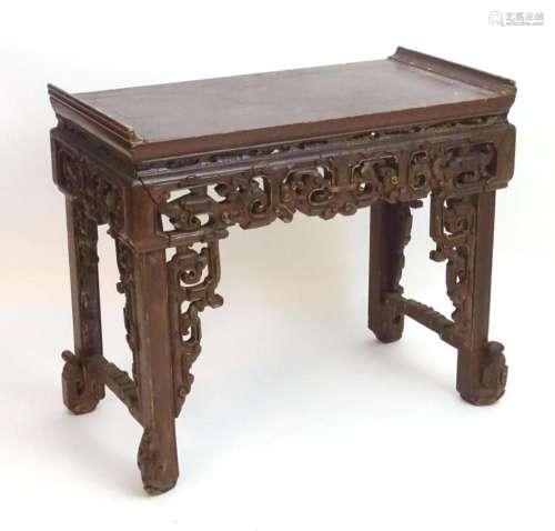 A 19thC Chinese lacquered table with raised ends and carved ...