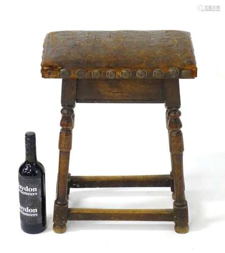 An early 20thC peg jointed oak stool with an embossed leathe...