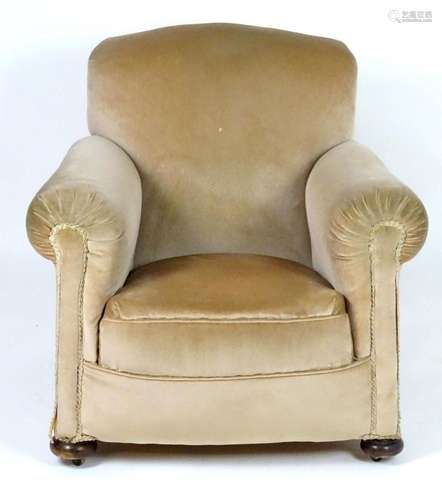 A mid 20thC Howard style armchair with scrolled arms and rai...