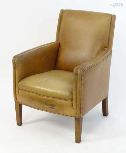 A late 20thC tan leather armchair with studwork detailing an...