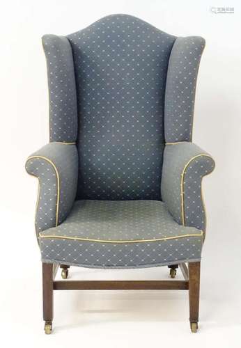 A 19thC wingback armchair with a shaped top above scrolled a...