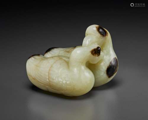 A PALE CELADON AND BLACKISH-BROWN JADE CARVING OF TWO RECUMB...