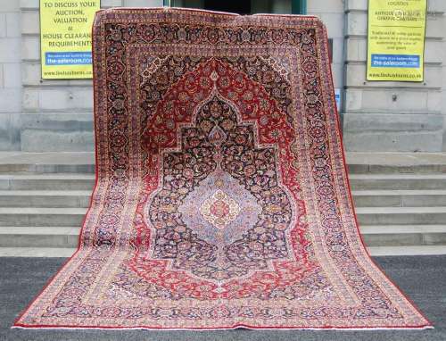 An early 20th century Persian Kashan carpet, the deep red fi...