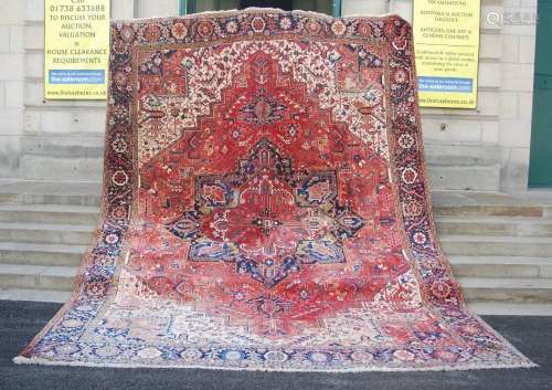 A large early 20th century Persian Heriz carpet, the deep re...