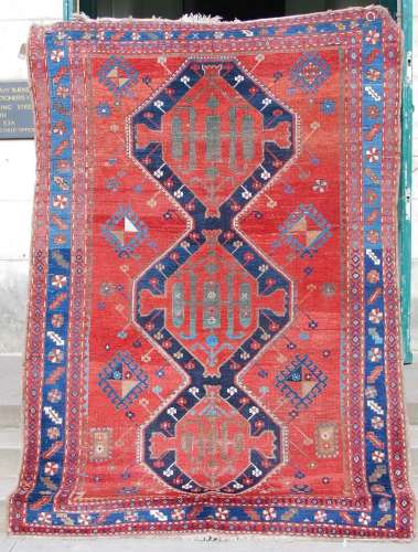 An antique Persian carpet, the deep red field with three lin...