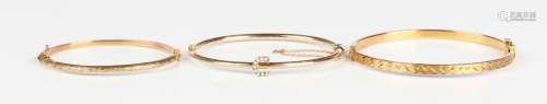 A gold and seed pearl oval hinged bangle with a horseshoe sh...