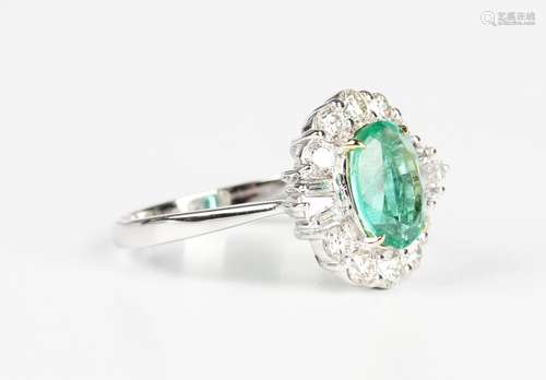 A white gold, emerald and diamond cluster ring, claw set wit...