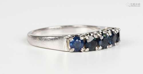 A white gold and sapphire ring, claw set with a row of five ...