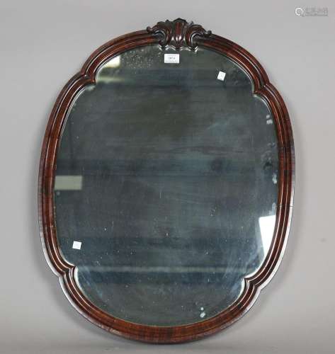 A Victorian mahogany shaped oval wall mirror with leaf scrol...