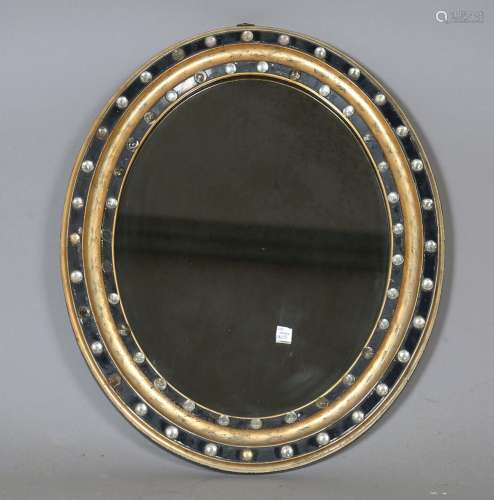 A 19th century Irish ebonized and gilded oval wall mirror wi...
