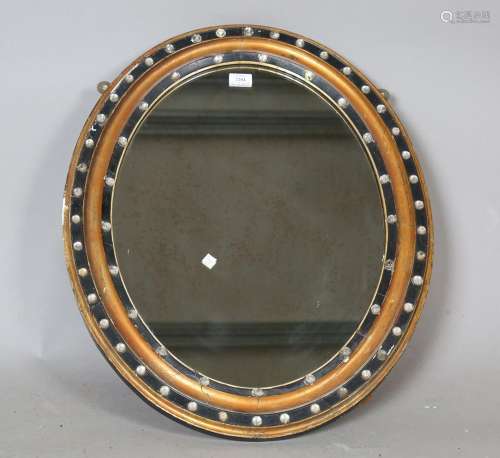 A 19th century Irish ebonized and gilded oval wall mirror wi...