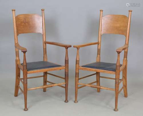 A pair of Edwardian Arts and Crafts oak elbow chairs designe...