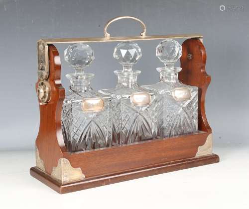 A late 20th century mahogany three-bottle tantalus, the silv...
