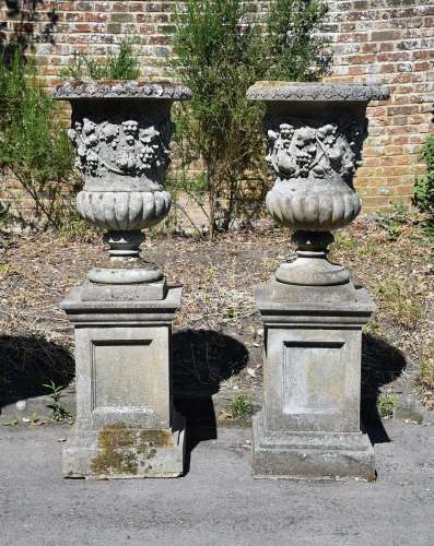 A PAIR OF COMPOSITION STONE VINE PATTERN URNS ON STANDS, IN ...