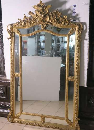 Miroir en bois sculpté et doré, le fronton à décor de deux p...