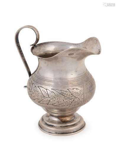 An antique Russian silver creamer with engraved floral desig...