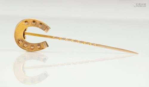 An antique yellow gold luck horseshoe stickpin in a plush fi...