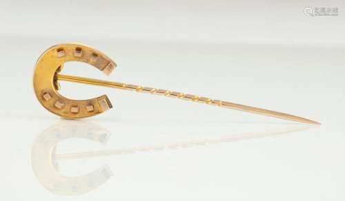 An antique yellow gold luck horseshoe stickpin in a plush fi...