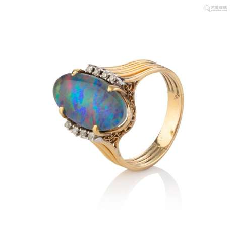 A yellow gold ring set with an oval opal doublet flanked by ...