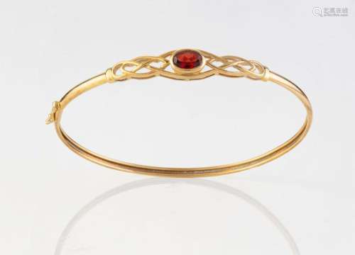 A 9ct yellow gold bangle with a red garnet, 20th century, 6....
