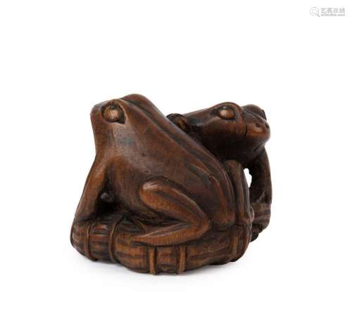 An antique Japanese carved boxwood netsuke of two frogs on a...