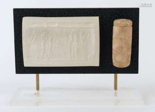 An ancient marble cylinder seal, the imprint depicting a mal...